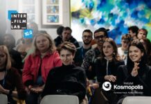 Uczestnicy i uczestniczki warsztatów INTERFILMLAB uczestniczący w wykładzie. Loga INTERFILMLAB 10.0 oraz Instytutu Kosmopolis Fundacja Nauki, Kultury i Edukacji.