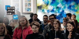 Uczestnicy i uczestniczki warsztatów INTERFILMLAB uczestniczący w wykładzie. Loga INTERFILMLAB 10.0 oraz Instytutu Kosmopolis Fundacja Nauki, Kultury i Edukacji.